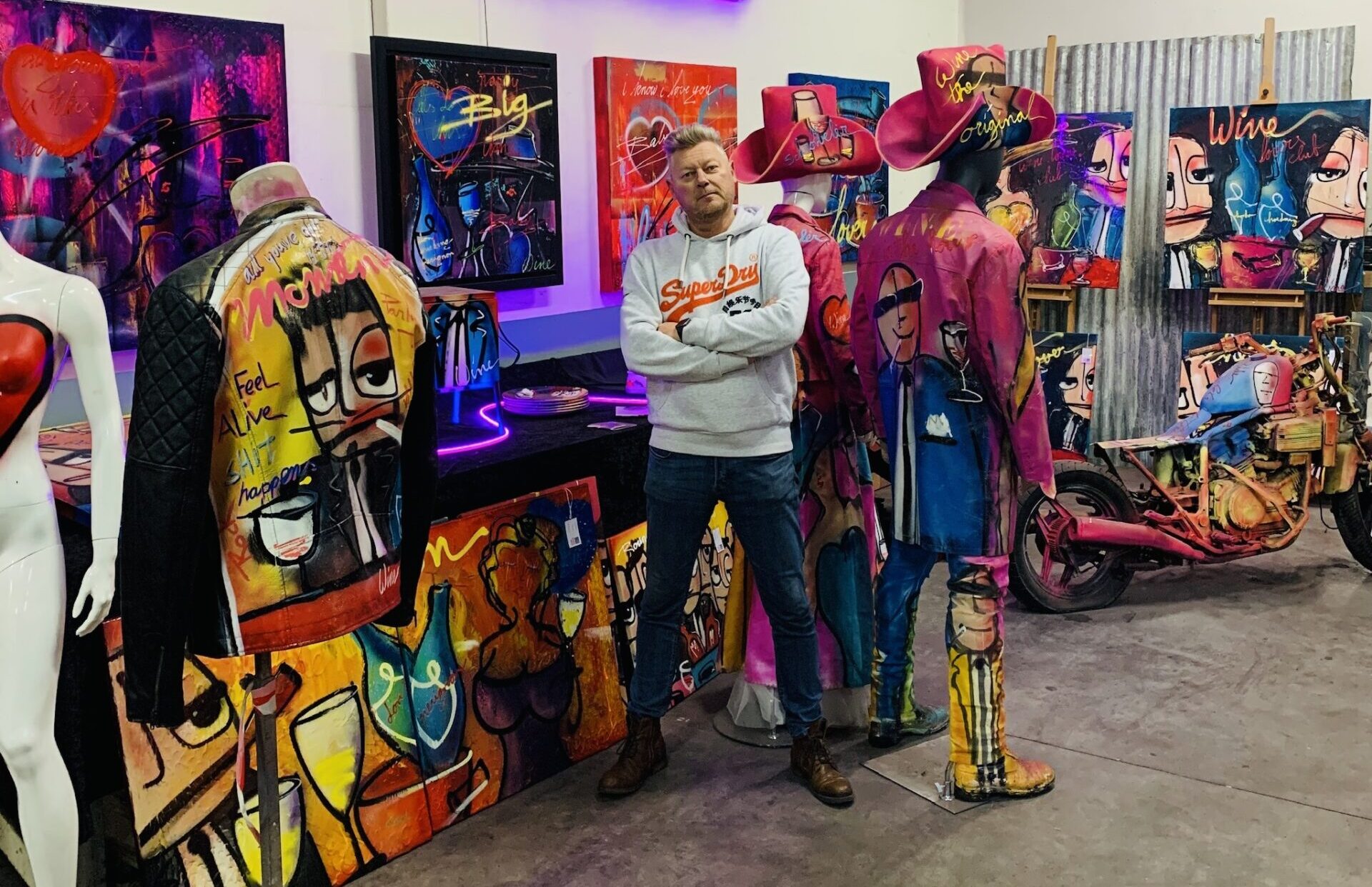 Kunstenaar Geoffrey Wijn temidden van zijn kleurrijke kunstwerken in zijn atelier in Roosendaal.